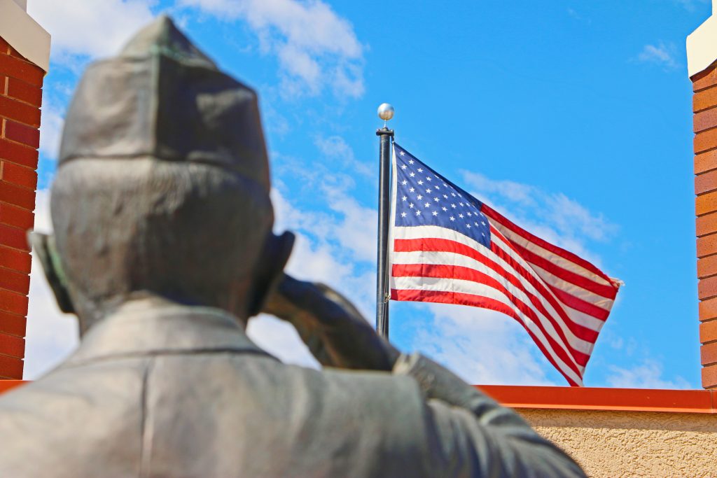 Salute to Veterans: Statue of soldier saluting with American flag flying in the background.