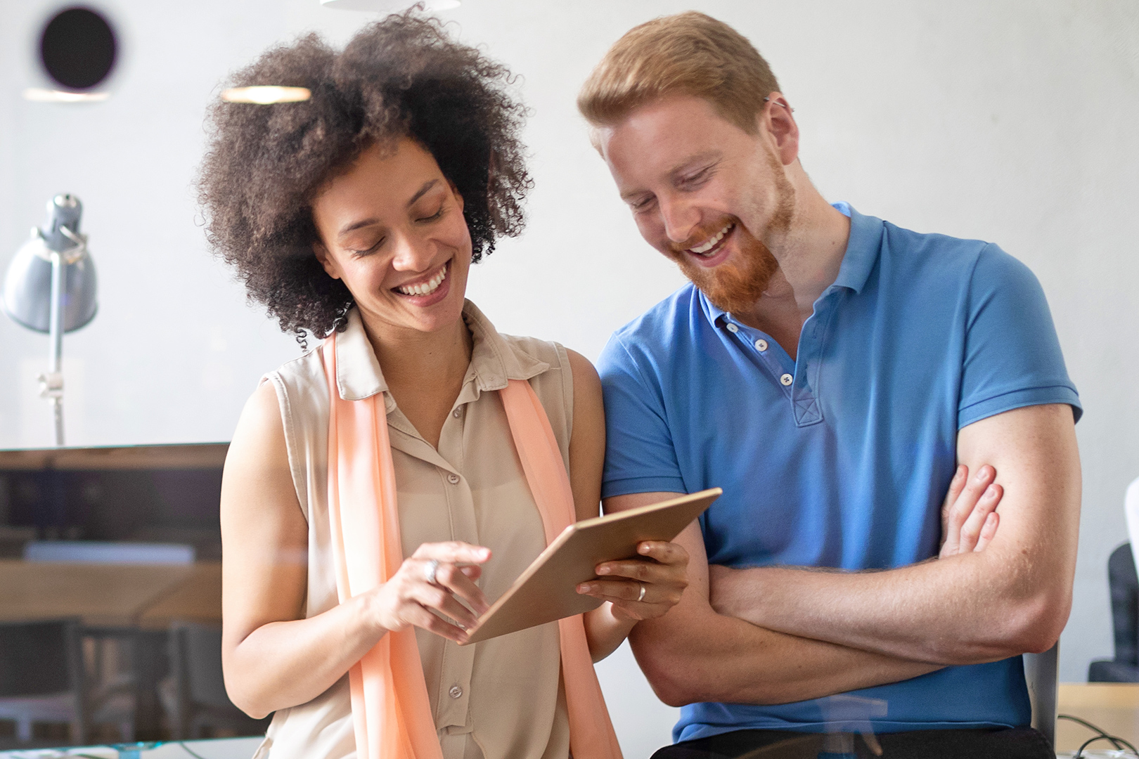 African american woman holding a notepad and caucasian man having a happy conversation at work