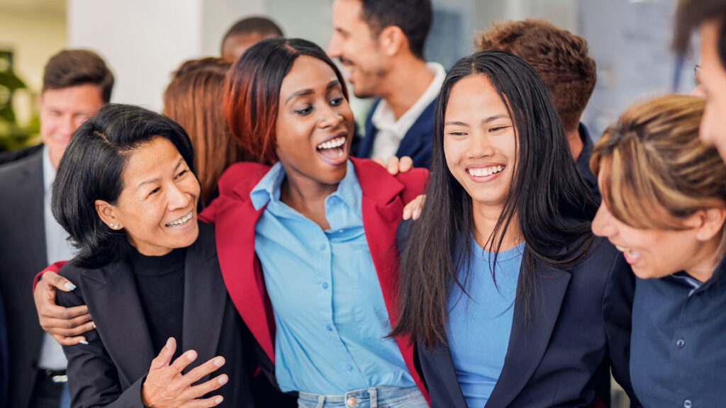 A group of smiling women hugging each other at a friendly networking event.
