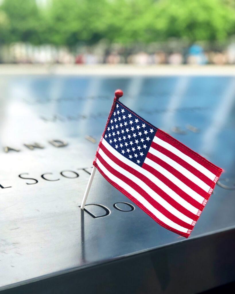 A small American flag rests on top of carved names at the 9/11 memorial.